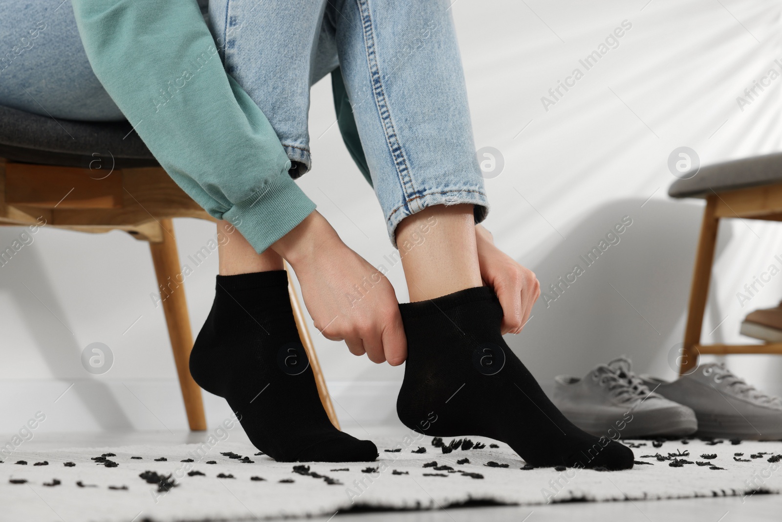 Photo of Woman putting on black socks at home, closeup