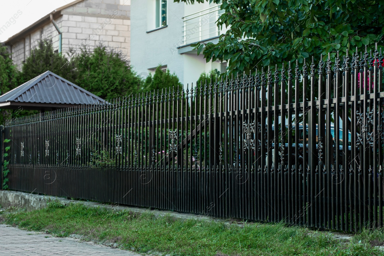 Photo of Beautiful black iron fence near pathway outdoors