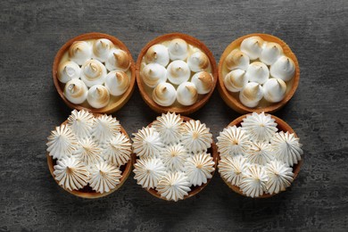 Photo of Many different tartlets with meringue on dark grey table, flat lay. Tasty dessert