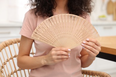 Woman with hand fan indoors, closeup view