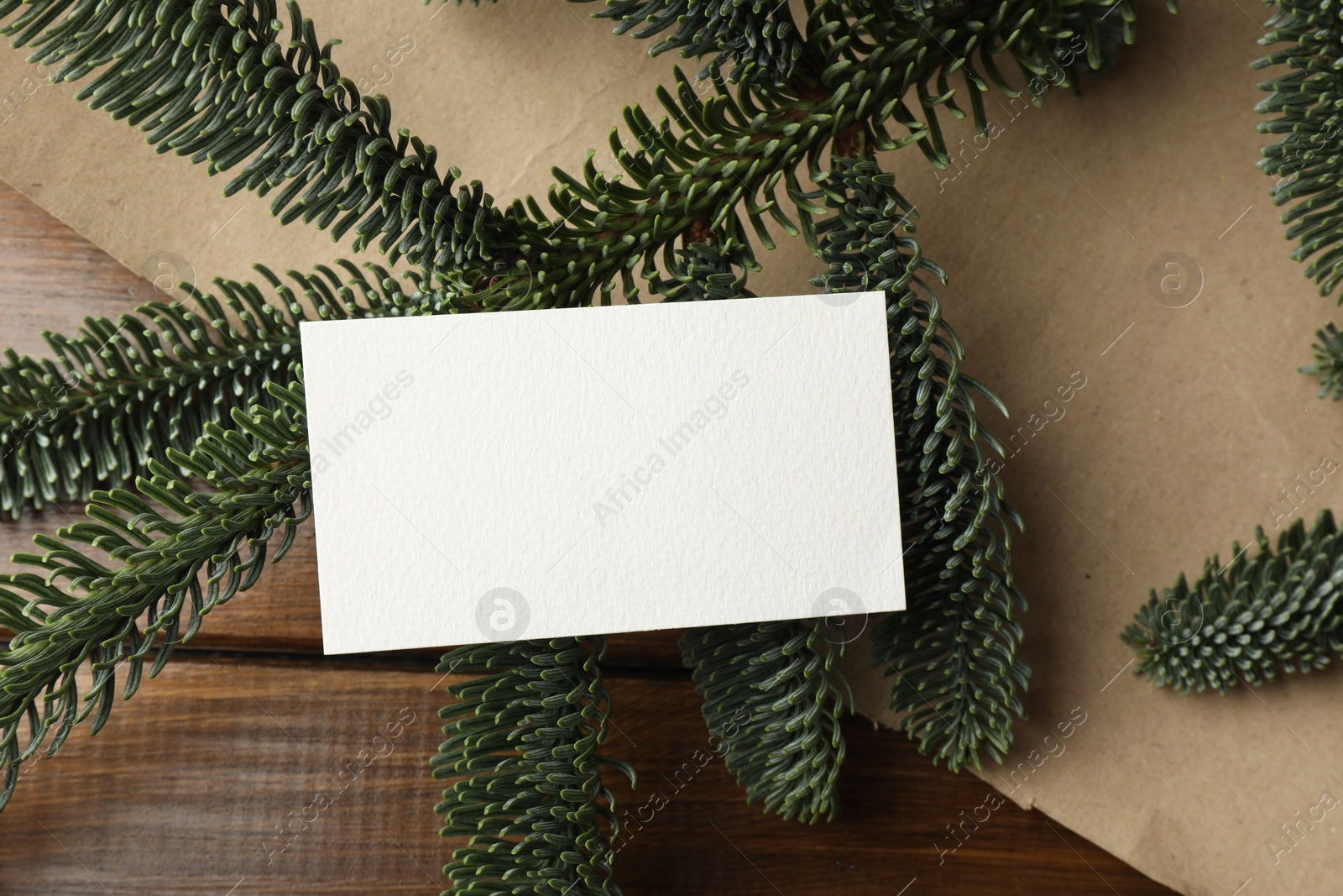 Photo of Blank business card and fir branches on wooden table, flat lay. Space for text