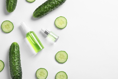 Photo of Flat lay composition with fresh cucumber, cosmetic bottles and space for text on white background