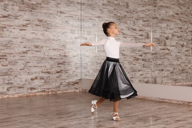 Photo of Adorable little girl dancing in studio, space for text