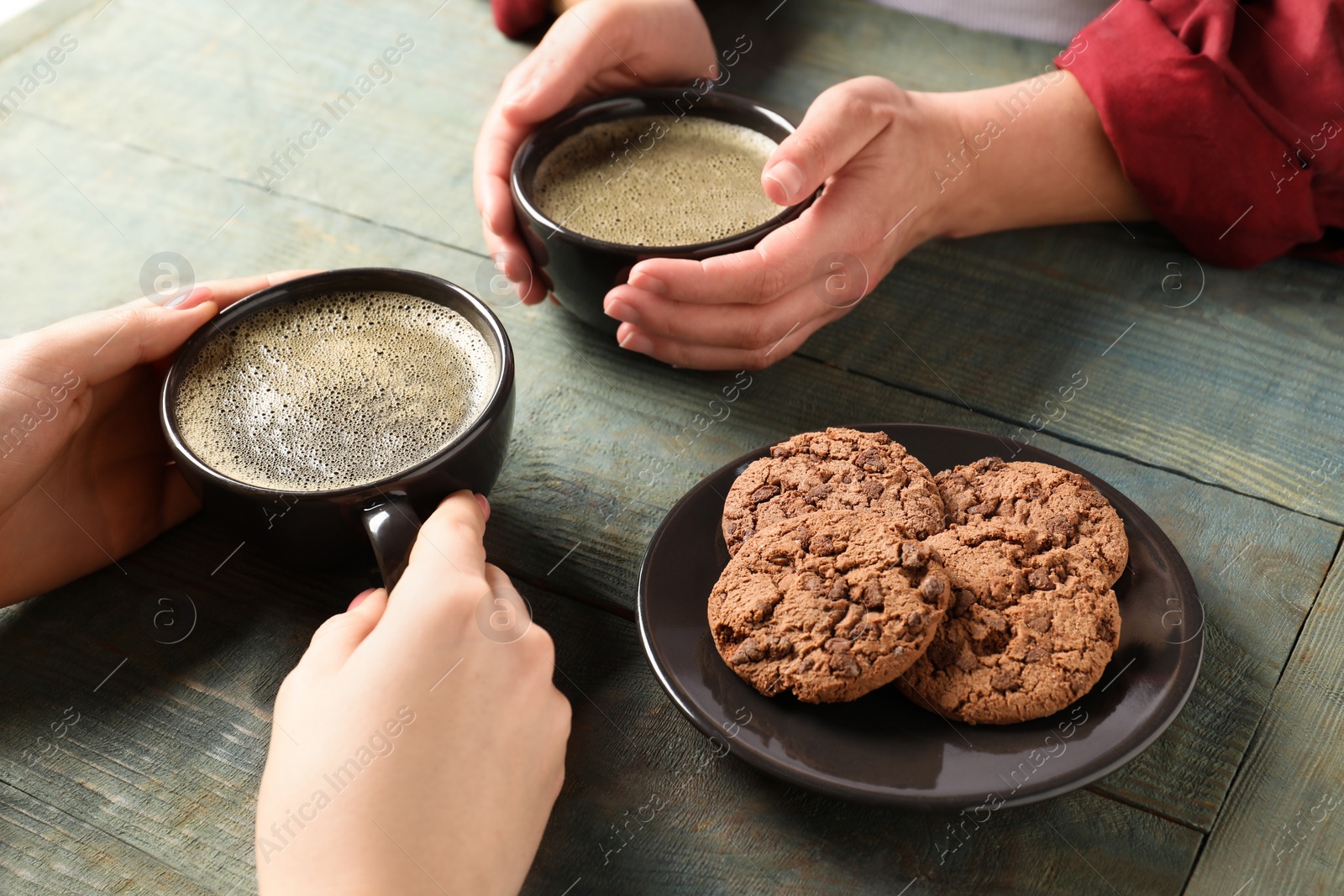 Photo of Women having coffee break at rustic wooden table, closeup