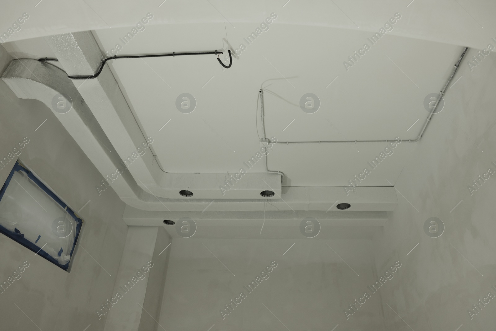 Photo of Ventilation system and wires on white ceiling indoors