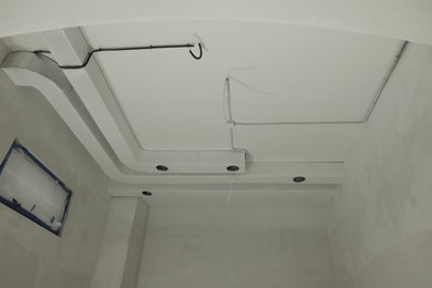 Ventilation system and wires on white ceiling indoors