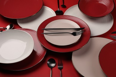 Stylish table setting with cutlery on red background