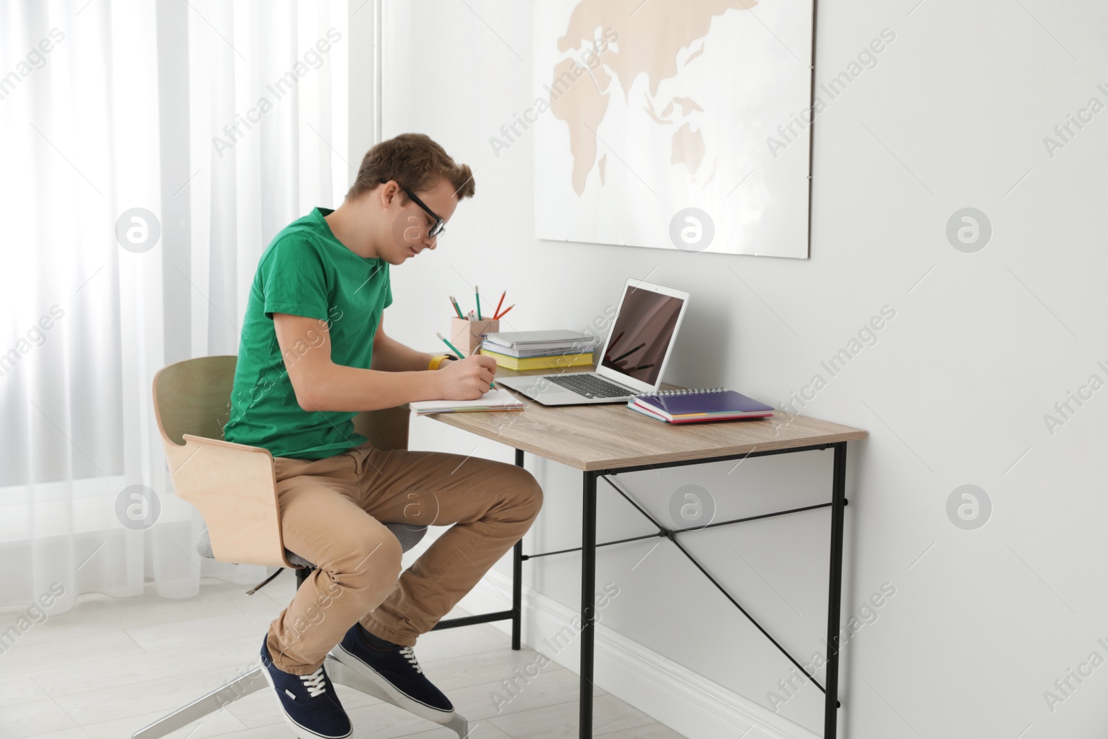 Photo of Teenager boy doing his homework at desk indoors