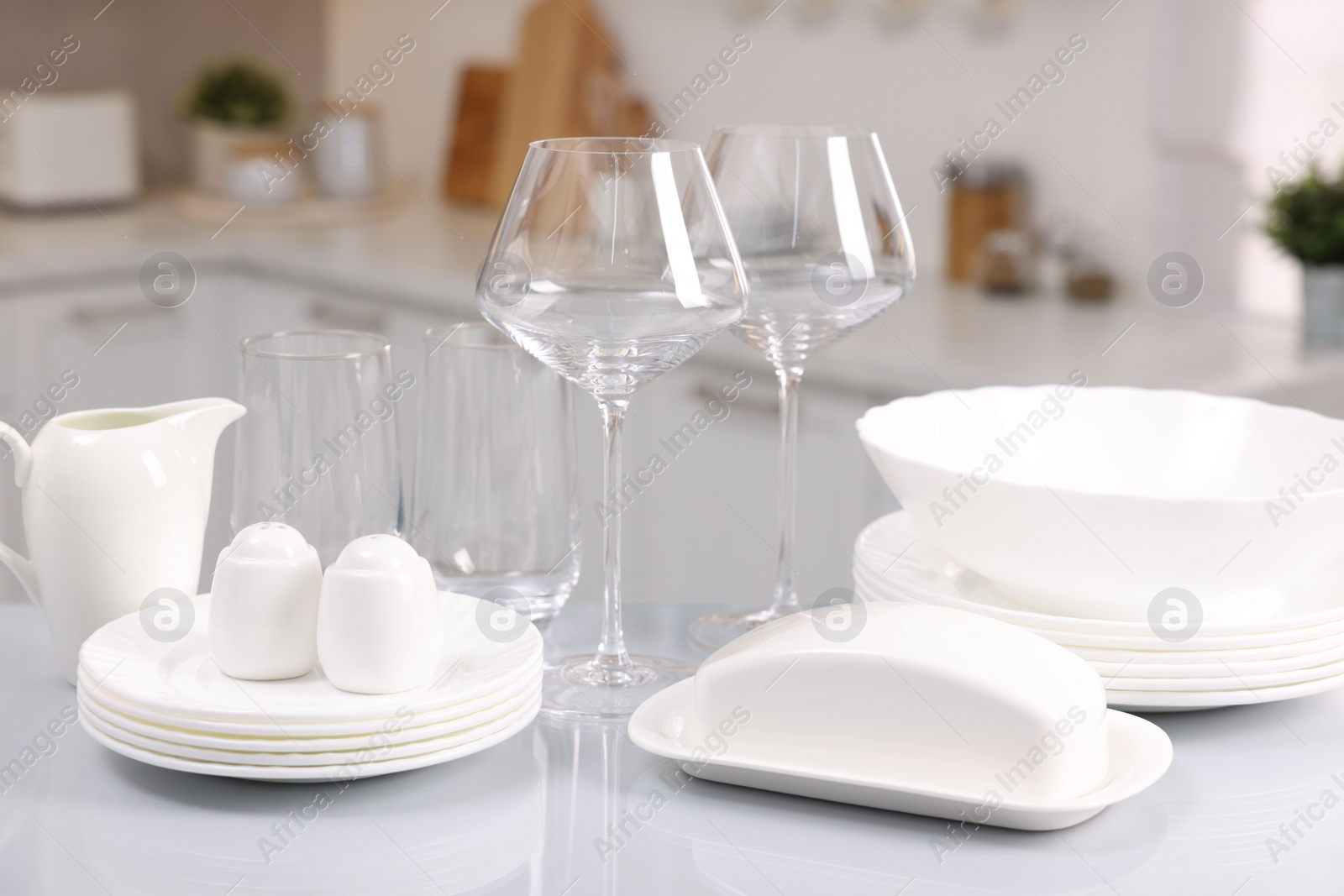 Photo of Set of clean dishware and glasses on table in kitchen