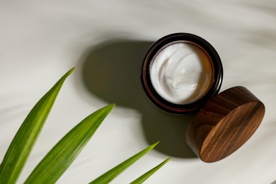 Photo of Open jar of cosmetic cream on white table, top view