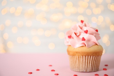 Photo of Tasty cupcake on pink table against blurred lights, space for text. Valentine's Day celebration