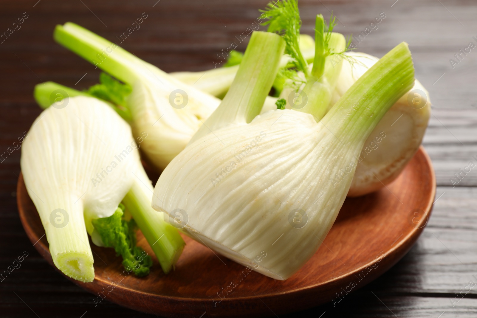 Photo of Fresh raw fennel bulbs on wooden table, closeup