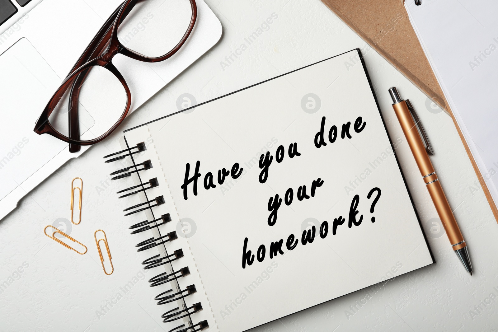 Image of Stylish notebook with phrase HAVE YOU DONE YOUR HOMEWORK? on table, flat lay 