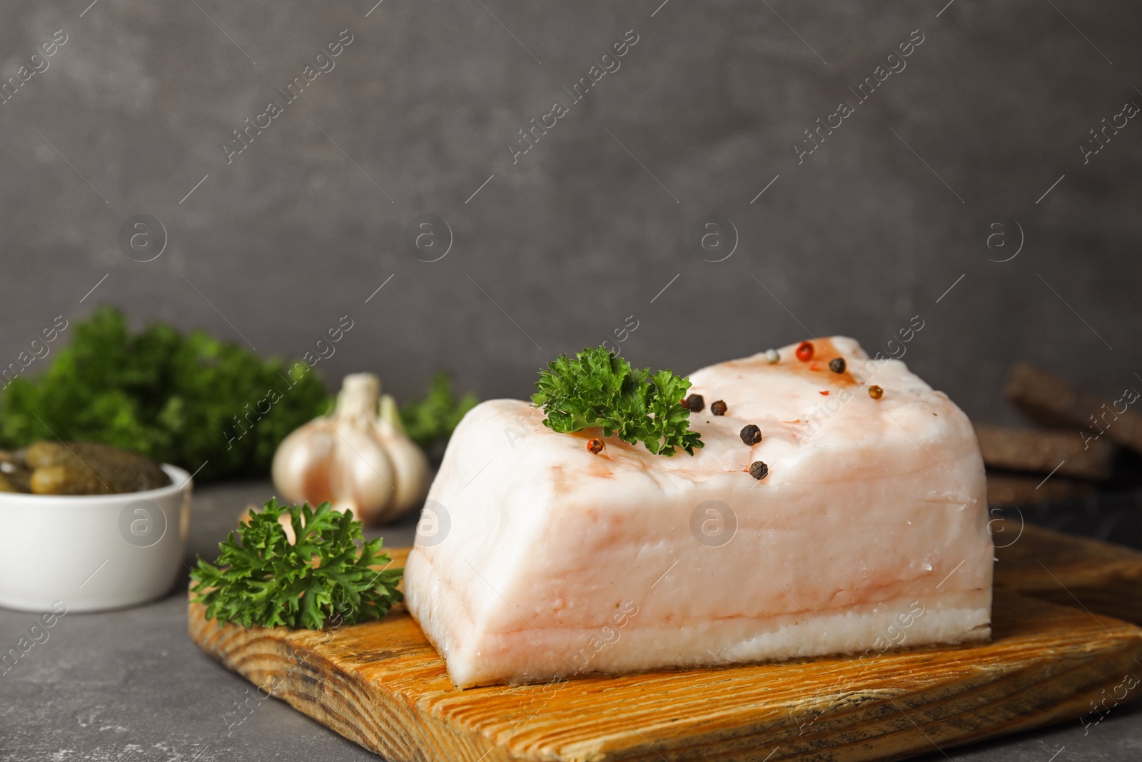 Photo of Composition with pork fatback on grey stone table. Space for text