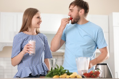 Photo of Young couple preparing delicious milk shake in kitchen