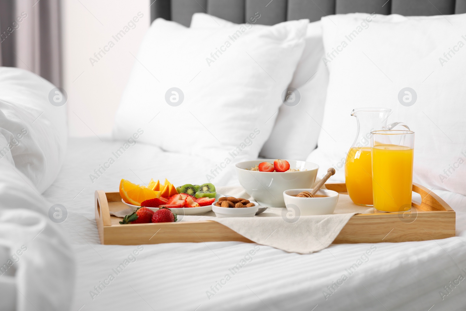 Wooden tray with tasty breakfast on bed at home Photo of Wooden tray with tasty breakfast on bed at home