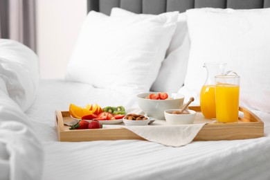 Photo of Wooden tray with tasty breakfast on bed at home