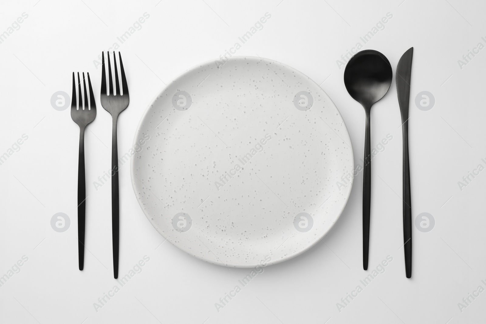 Photo of Empty plate, forks, spoon and knife on white background, flat lay