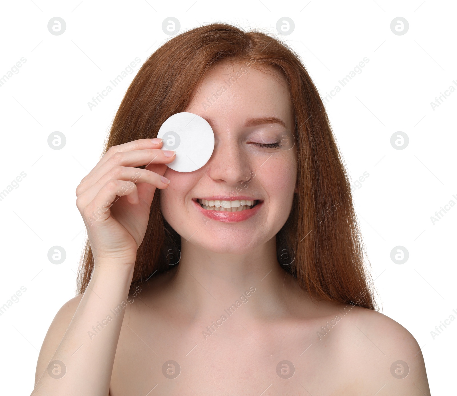 Photo of Smiling woman with freckles covering eye with cotton pad on white background