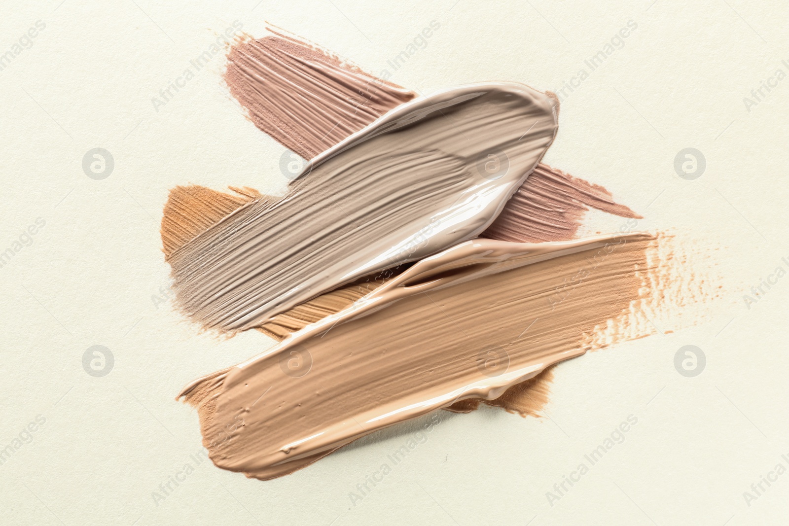 Image of Different shades of liquid foundation on beige background, top view