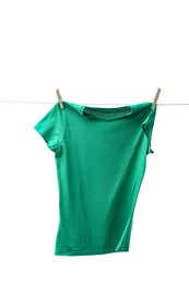 Photo of One green t-shirt drying on washing line isolated on white