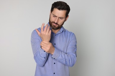 Photo of Man suffering from pain in his hand on light background. Arthritis symptoms