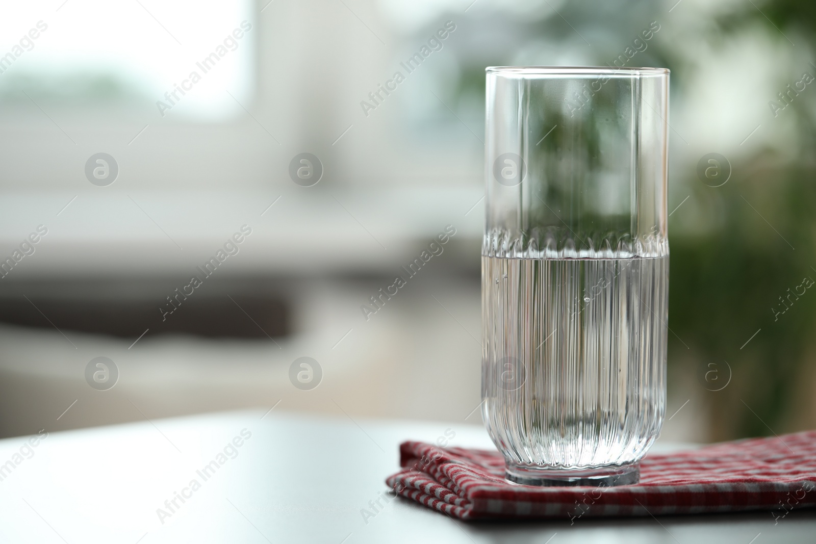 Photo of Glass of pure water on light table against blurred background, space for text