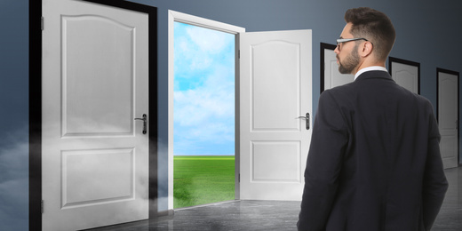 Image of Young man standing in front of many doors. Choice concept