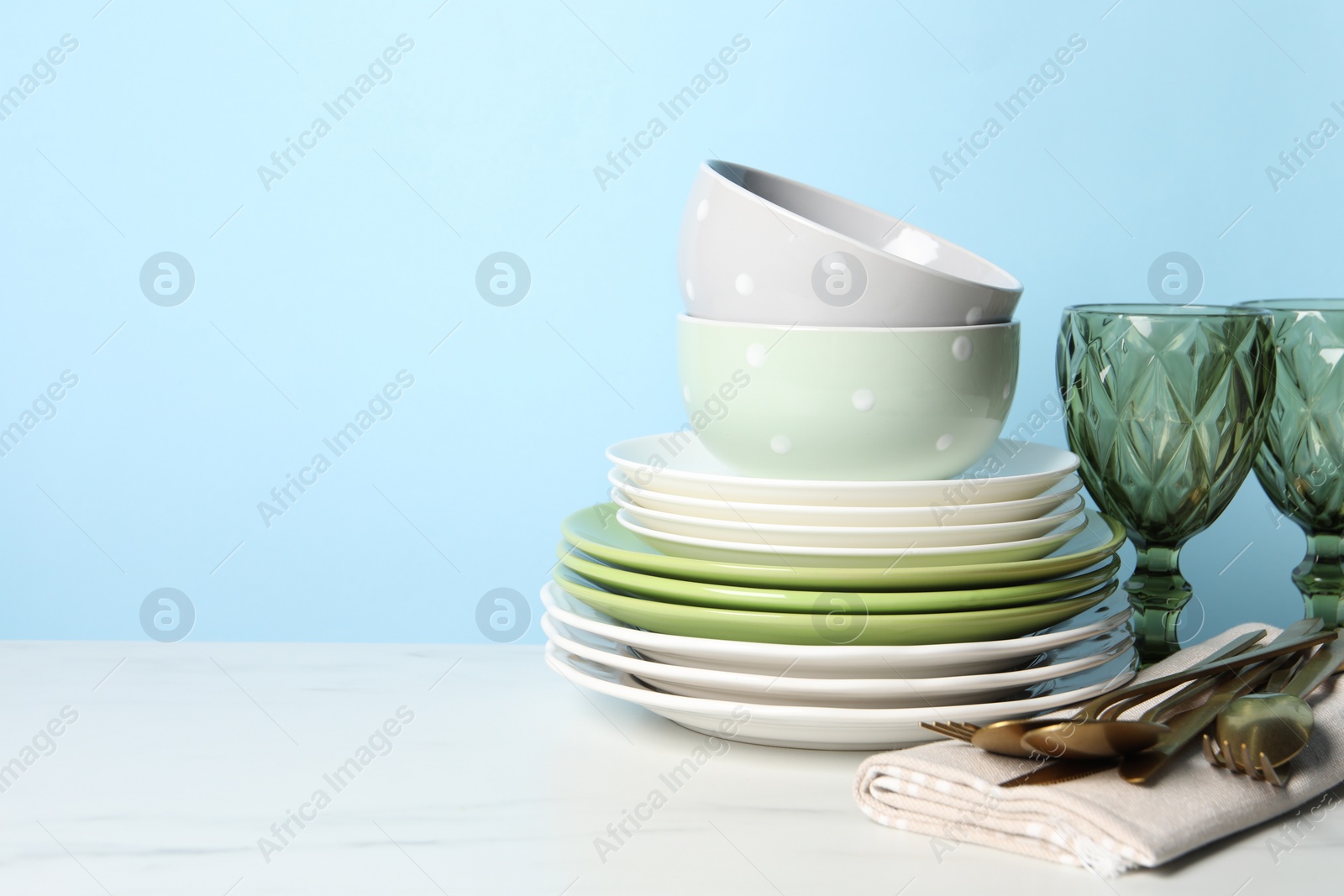 Photo of Beautiful ceramic dishware, glasses and cutlery on white marble table. Space for text