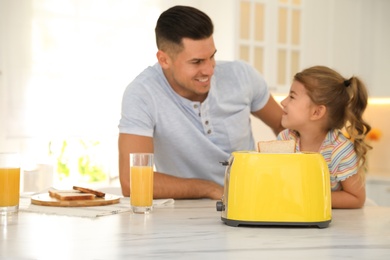 Father and daughter near modern toaster at kitchen table