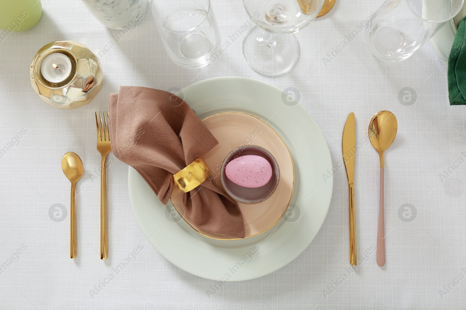 Photo of Festive Easter table setting with painted egg and burning candle, flat lay