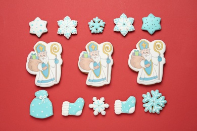 Tasty gingerbread cookies on red background, flat lay. St. Nicholas Day celebration