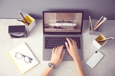 Image of Woman searching hotel using laptop at table, top view. Booking online service