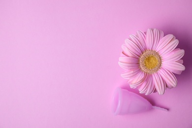 Photo of Flat lay composition with menstrual cup and gerbera flower on color background, space for text. Gynecological care