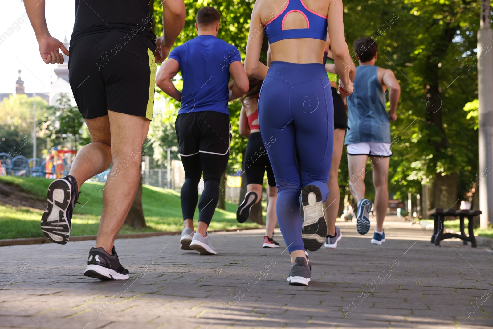 Photo of Group of people running in park, back view