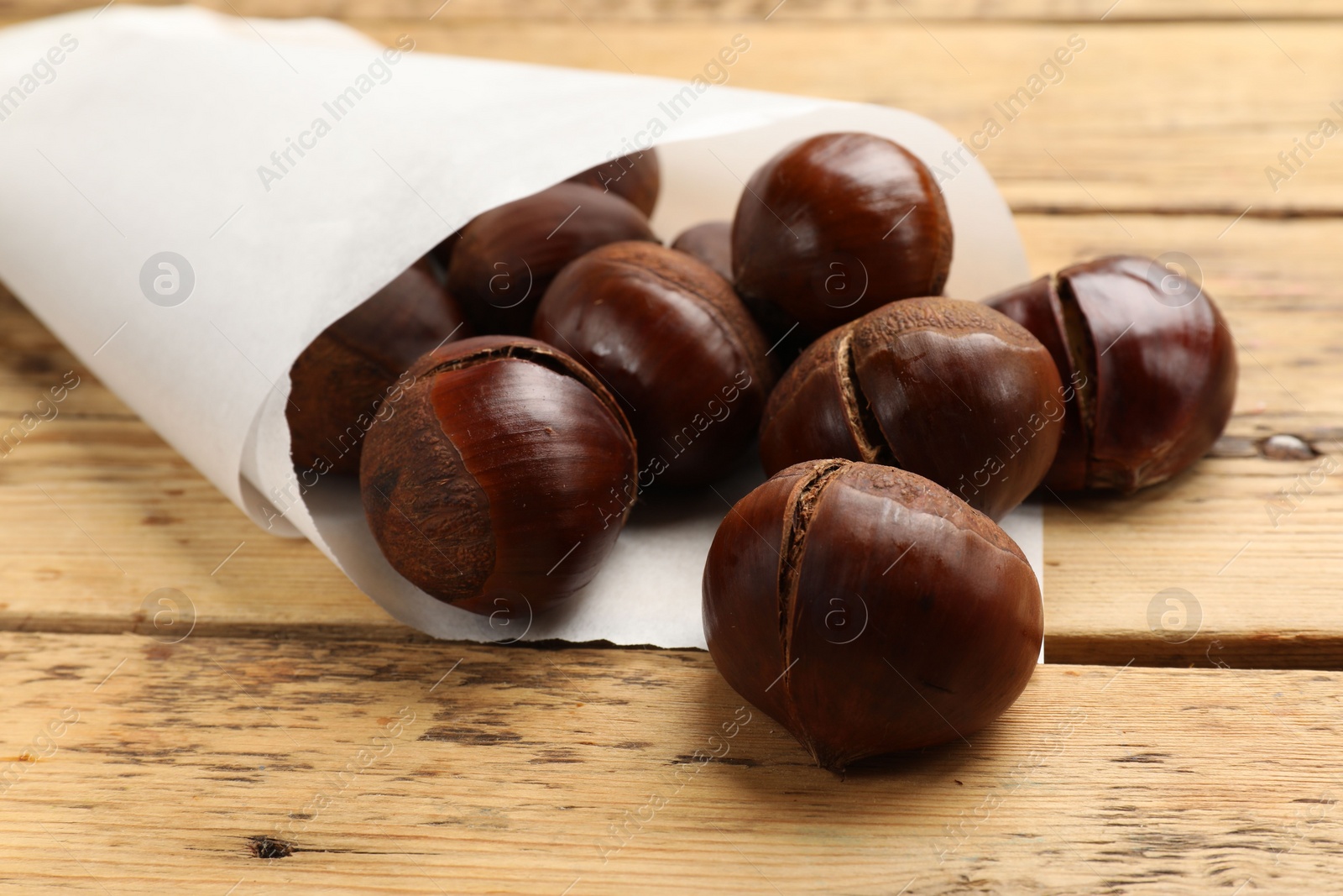 Photo of Fresh edible sweet chestnuts on wooden table, closeup