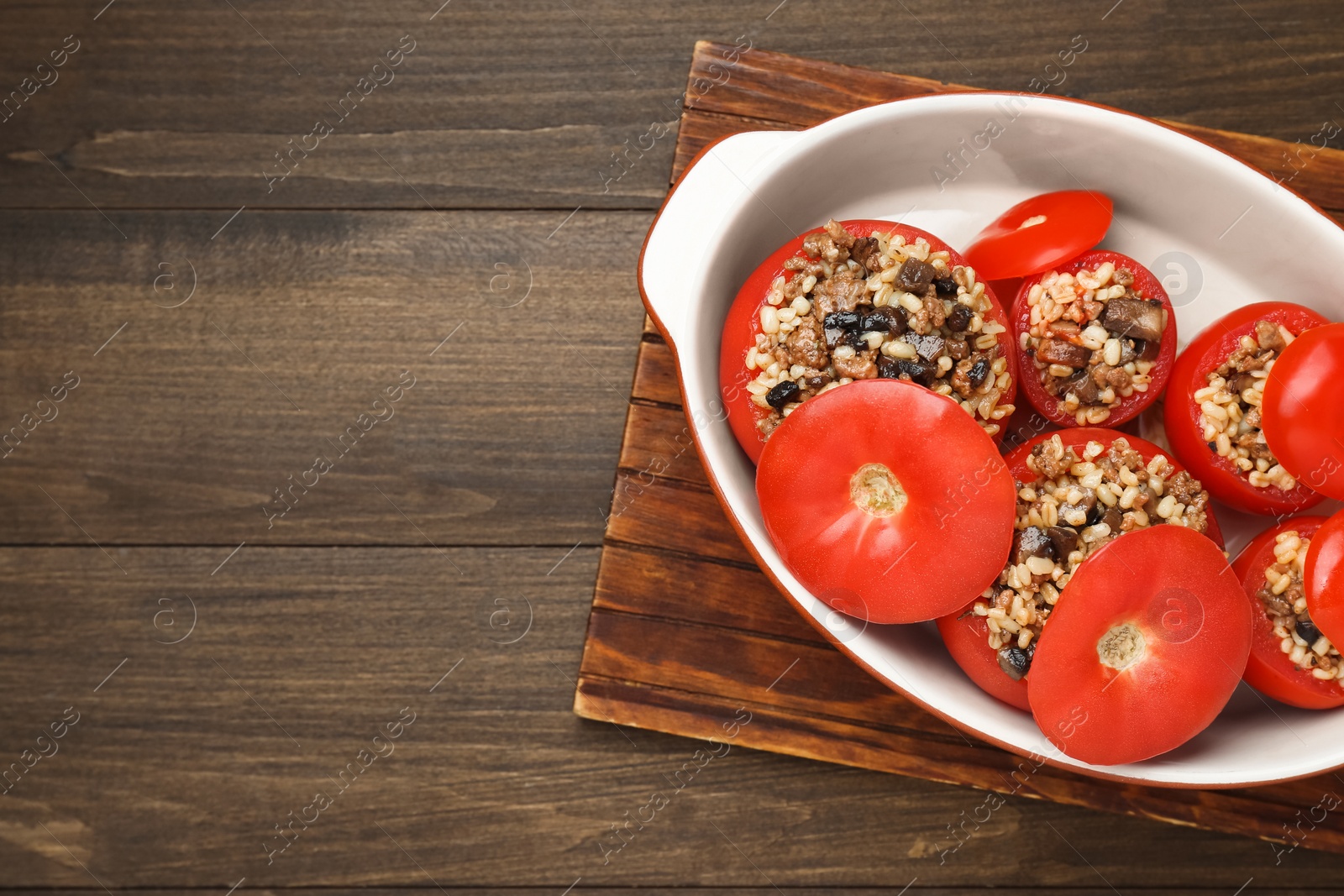 Photo of Delicious stuffed tomatoes with minced beef, bulgur and mushrooms on wooden table, top view. Space for text