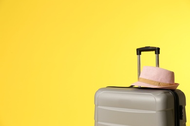 Photo of Stylish suitcase with hat on color background. Space for text