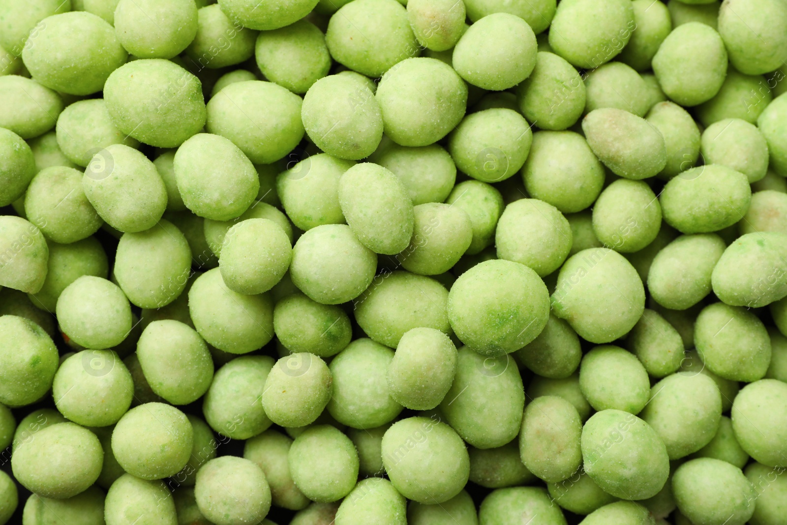 Photo of Tasty wasabi coated peanuts as background, top view