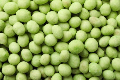 Tasty wasabi coated peanuts as background, top view