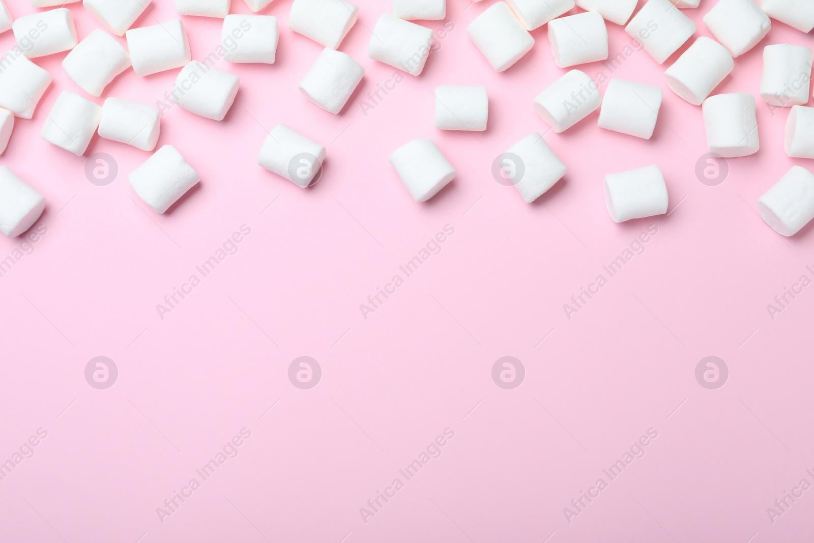Photo of Delicious puffy marshmallows on pink background, flat lay. Space for text