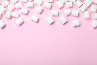 Delicious puffy marshmallows on pink background, flat lay. Space for text