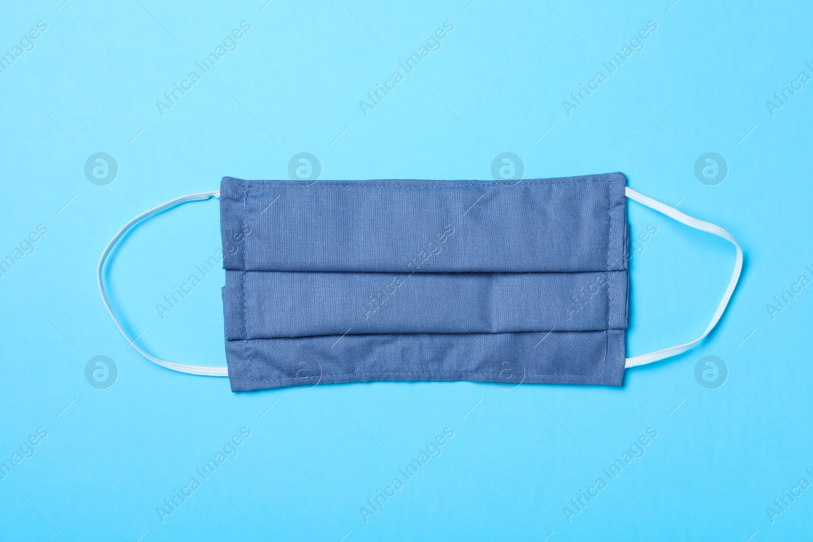 Photo of Homemade protective mask on light blue background, top view. Sewing idea