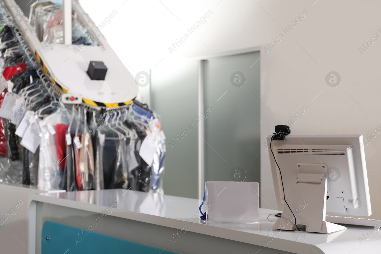 Photo of Modern dry-cleaner's interior with counter and garment conveyor