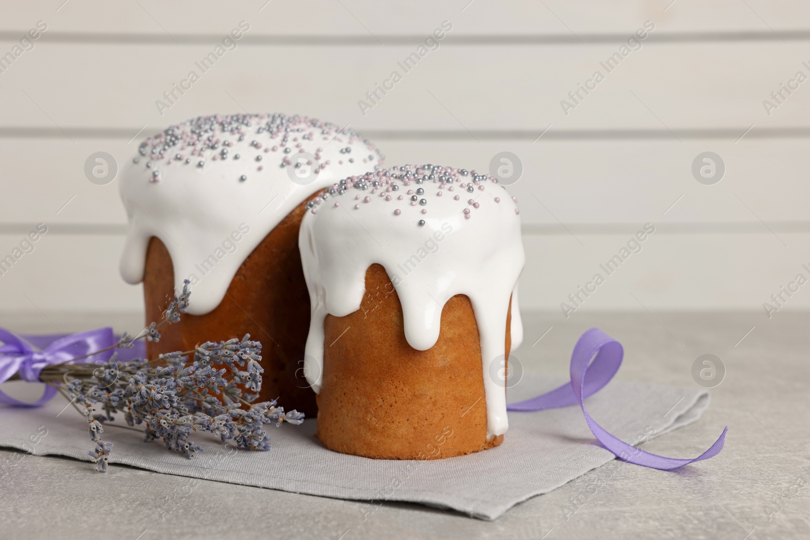 Photo of Tasty Easter cakes and lavender flowers on grey table. Space for text