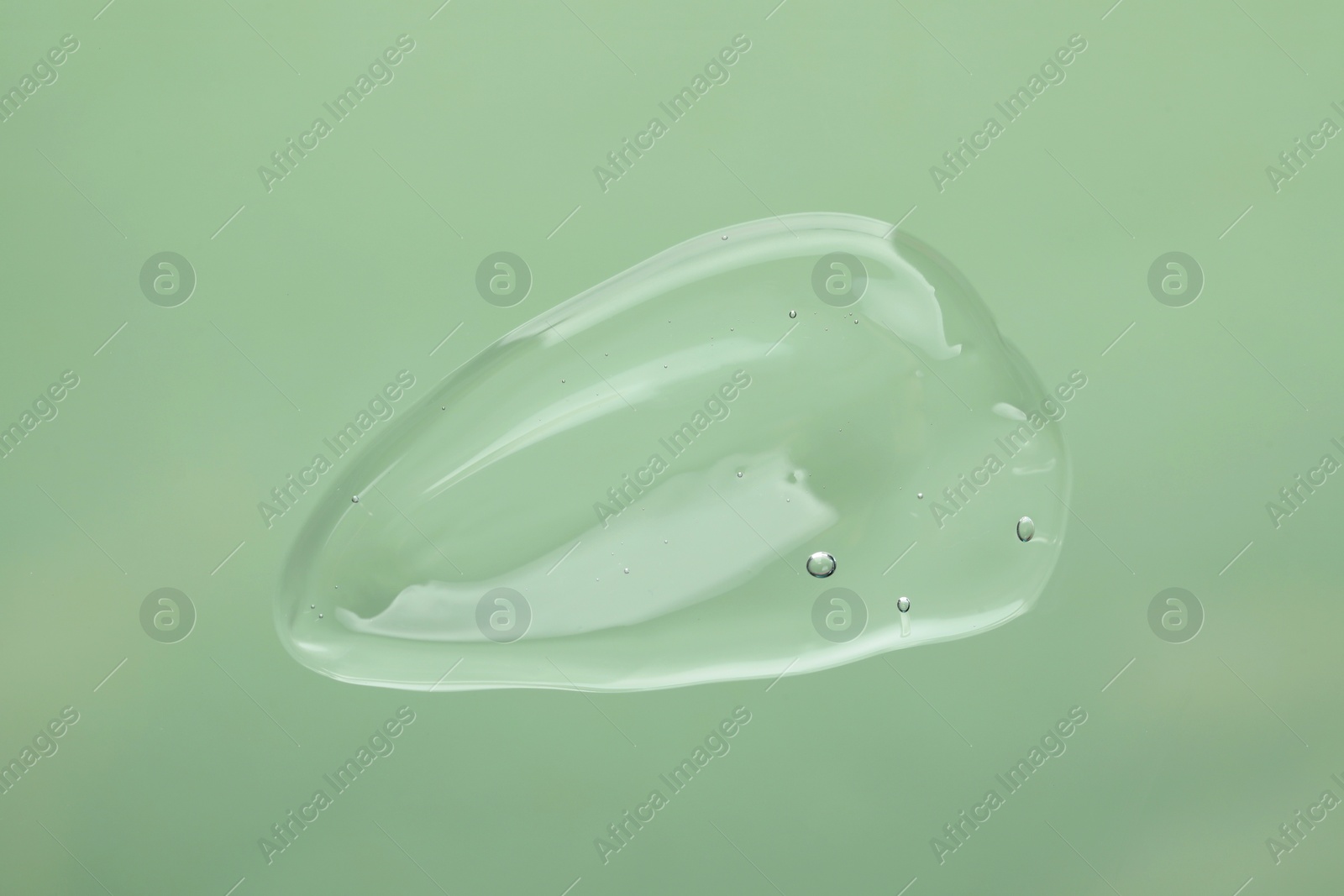 Photo of Sample of cleansing gel on pale green background, top view. Cosmetic product