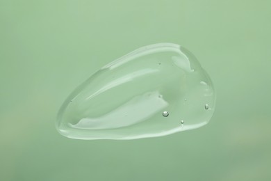 Photo of Sample of cleansing gel on pale green background, top view. Cosmetic product