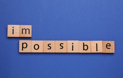 Photo of Motivation concept. Changing word from Impossible into Possible by removing squares with letters I and M on blue background, top view