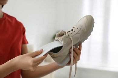 Woman putting orthopedic insole into shoe at home, closeup