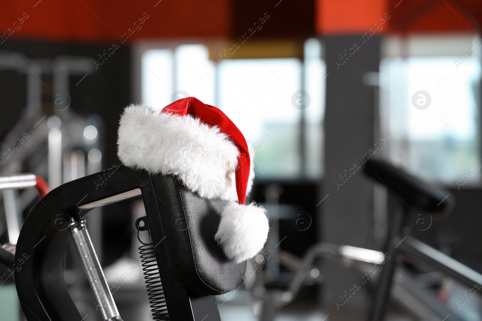 Photo of Santa Claus hat on modern exercise machine in gym